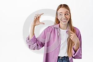 Blond woman holding something small and finy. Girl laughing while pointing at her hand showing little size tiny thing