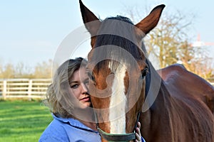 Blond woman hugs her  horse