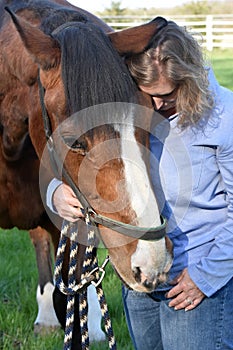 Blond woman hugs her  horse