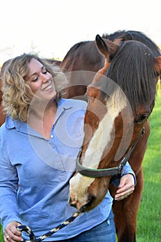 Blond woman hugs her  horse