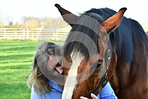 Blond woman hugs her  horse