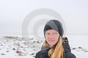 Blond woman with interrogative look and blue eyes on a white winter background