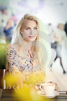 Blond woman on lunch break sit in summer outdoor cafe with cup of coffee