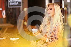 Blond woman on lunch break sit in summer outdoor cafe with cup o