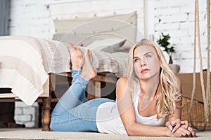 Blond woman lying on floor in bedroom