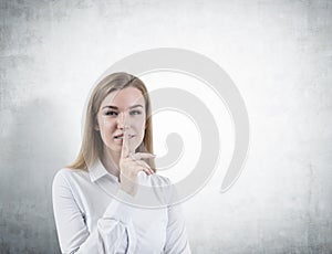 Blond woman making a hush sign concrete