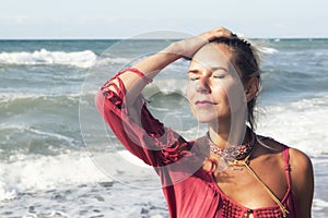 Blond woman in red dress standing by the ocean