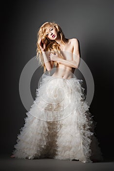 Blond woman in a romantic pose with white skirt