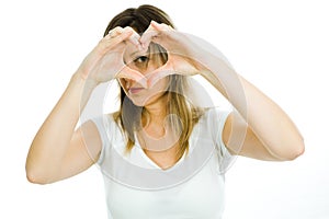 Blond woman shows heart shape with hands - looking through the heart - symbol of love