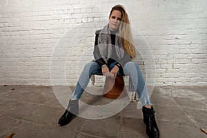 Blond woman sitting green eyes white brick wall