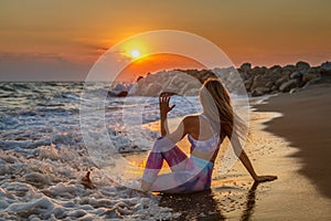 Blond woman sitting in a spinal twist position on the seashore