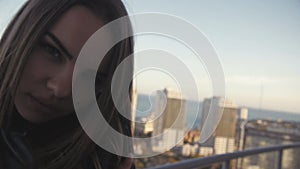 Blond Woman Smoking Basking in Blanket on High Floor at Buildings Background