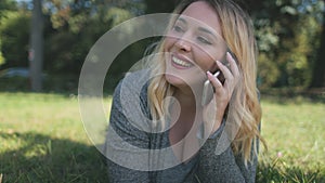 Blond woman speaking phone closeup. Attractive girl plus size lay, smile on grass. Nature landscape