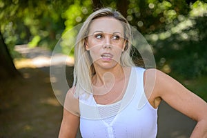 Blond woman standing biting her tongue deep in thought