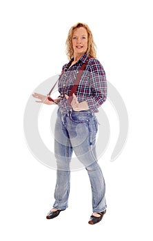 A blond woman standing in jeans and suspender.