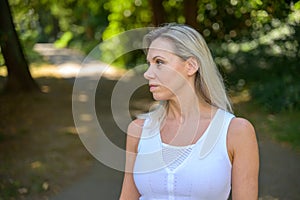 Blond woman standing in a shady country lane in summer