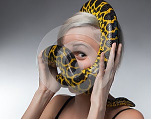 Blond woman and strangling yellow anaconda