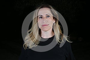 Blond woman studio portrait with black background