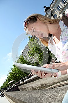Blond woman in town using tablet