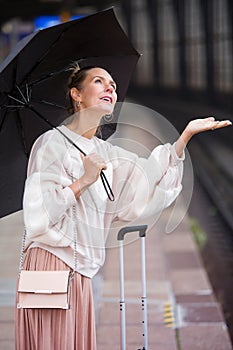 Blond woman with umbrella at train station