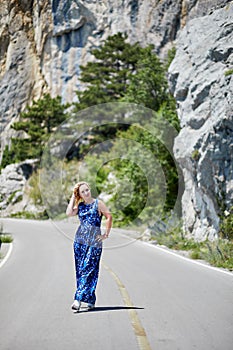 Blond woman walks asphalt road in mountainous photo