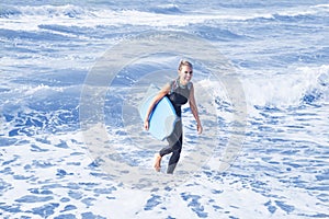 Blond woman in wetsuit and swimming board in the water