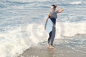 Blond woman in wetsuit walking out of the water