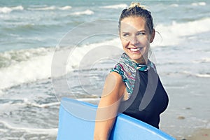 Blond woman in wetsuit walking out of the water