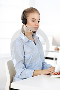 Blond woman working in sunny call center. Group of diverse people working as customer service occupation. Business