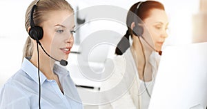 Blond woman working in sunny call center. Group of diverse people working as customer service occupation. Business