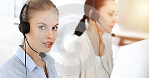 Blond woman working in sunny call center. Group of diverse people working as customer service occupation. Business