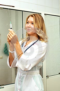 Blond young doctor in a white coat with a syringe Squirting the medicine before injection