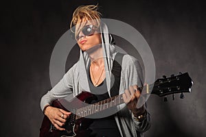 Blond young man with messy hair playing guitar in studio