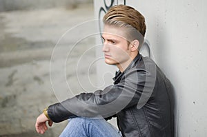 Blond young man sitting on stairs outside