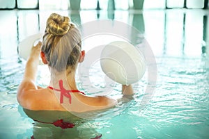 Blond young woman doing aqua aerobics with dumbbells in swimming