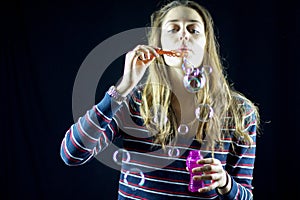 Blond young woman make a group of soap bubbles