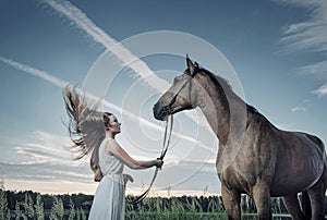 Blond young woman playing with a majestic stallion