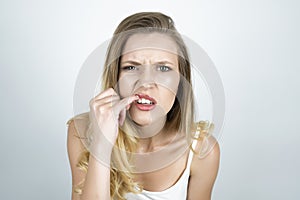 Blond young woman showing her teeth with finger close up isolated white background
