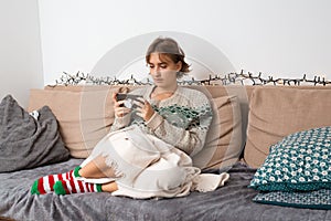 Blond young woman with sweater playing video game on her smart phone