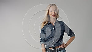 Blonde 30s woman alone in studio wears denim look