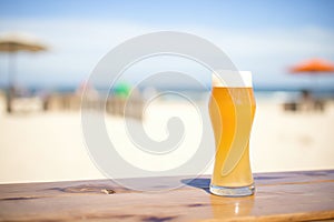 blonde ale in a pilsner glass, golden color, next to a sunny beach scene