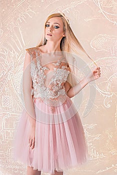 Blonde Attractive Woman, with Very Big Blue Eyes and Long Hair, with a Lace and Tulle Dress, Pulling Her Hair, on Pattern Pink