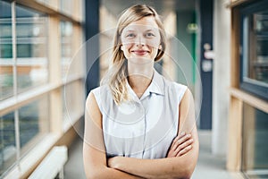 Blonde authentic businesswoman with crossed arms smiling