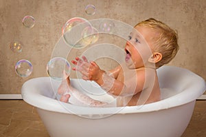 Blonde baby boy catching bubbles