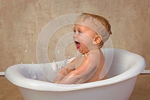 Blonde baby boy playful in bath