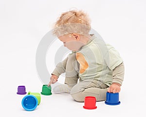 Blonde baby girl plays with colorful toys