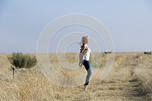 Blonde ballerina dancing in field