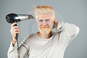 Blonde bearded man hair dry. Handsome man with long hair dries his hair with a hairdryer.