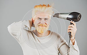 Blonde bearded man hair dry. Handsome man with long hair dries his hair with a hairdryer.