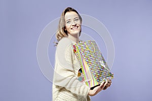 Blonde beautiful caucasian woman happy with present paper bags in hands. Wearing warm sweater, happy emotions.